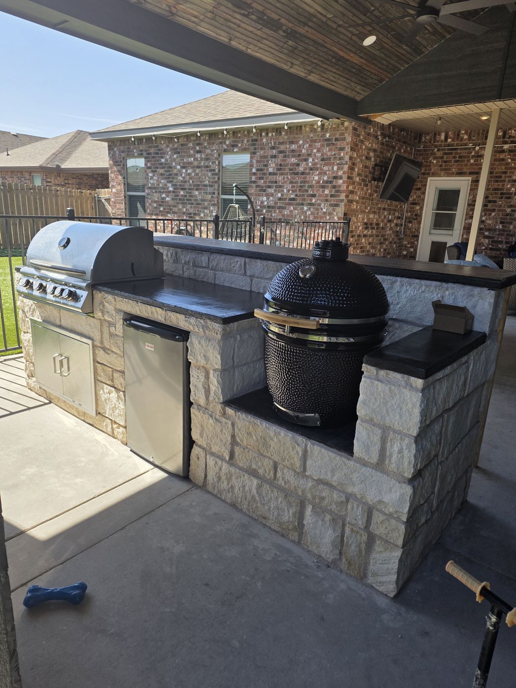 Covered-patio outdoor kitchen with limestone base, concrete countertops and kamado cooker in Desert Ridge, Odessa TX