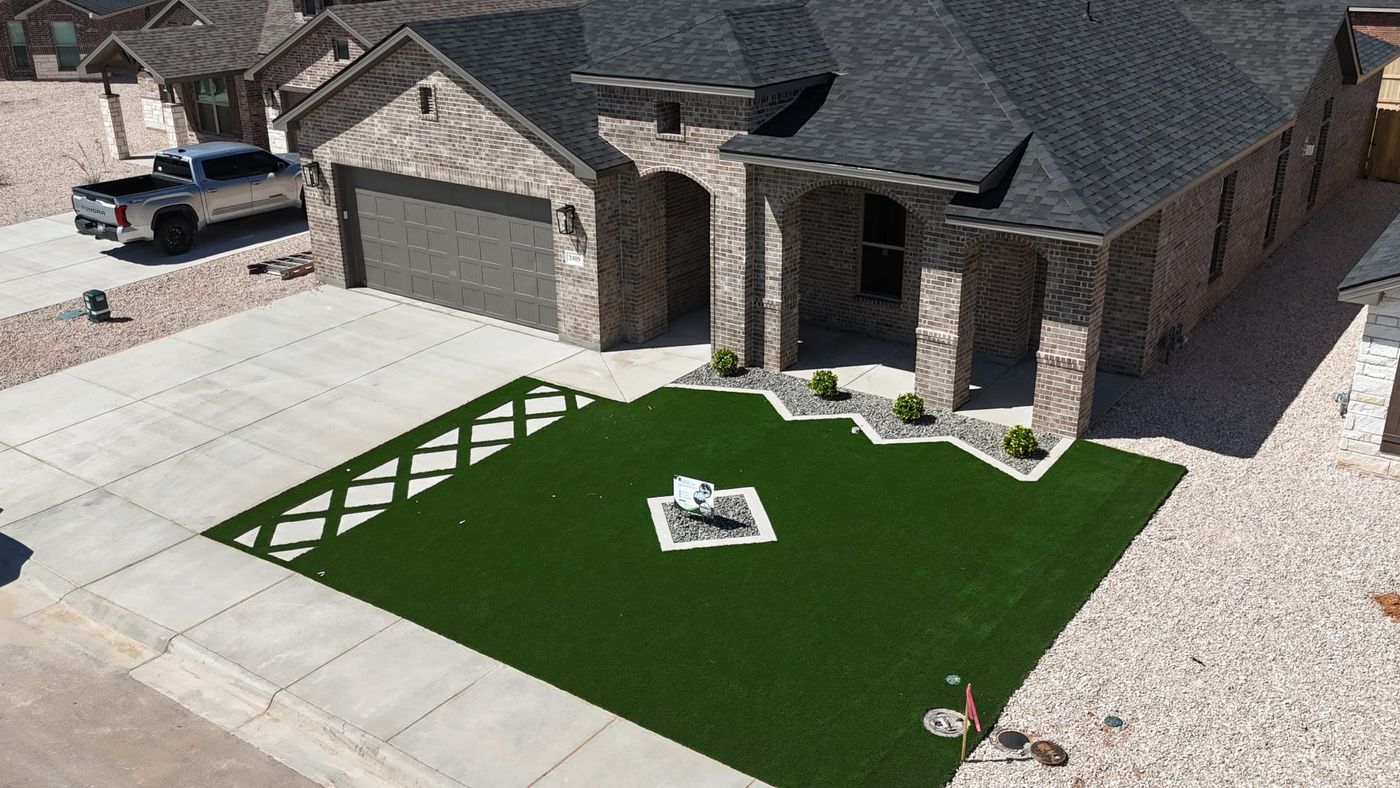 Aerial front-yard artificial turf lawn with gravel-and-shrub bed in Desert Ridge, Odessa TX
