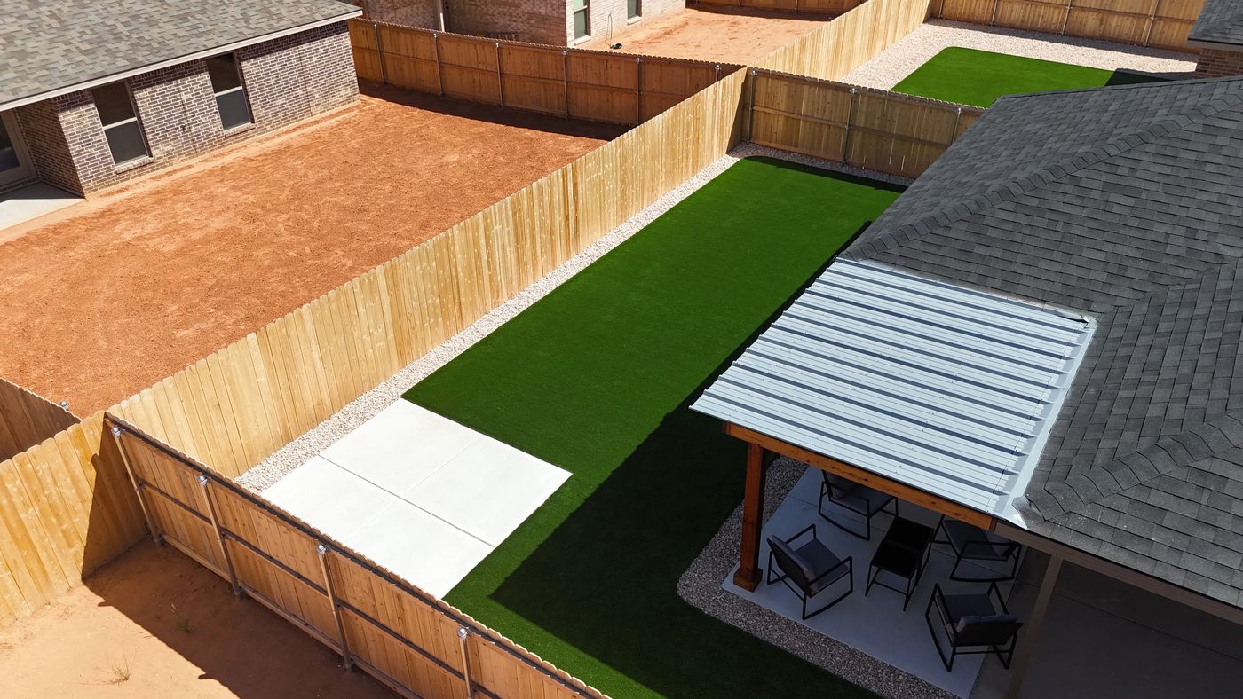 Aerial side-yard turf runner with concrete pad and metal-roof patio cover in Desert Ridge, Odessa TX