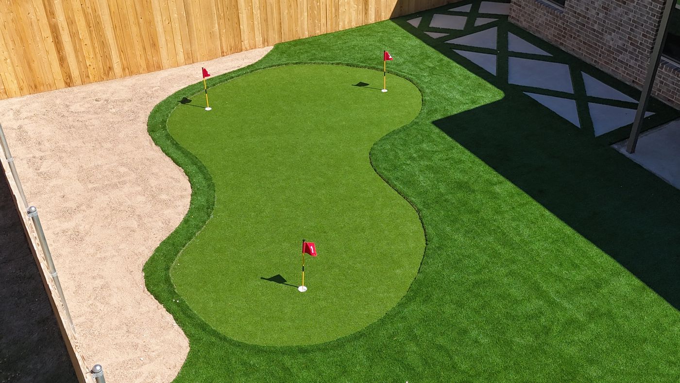 Freeform backyard putting green with flags and decomposed-granite border in Desert Ridge, Odessa TX