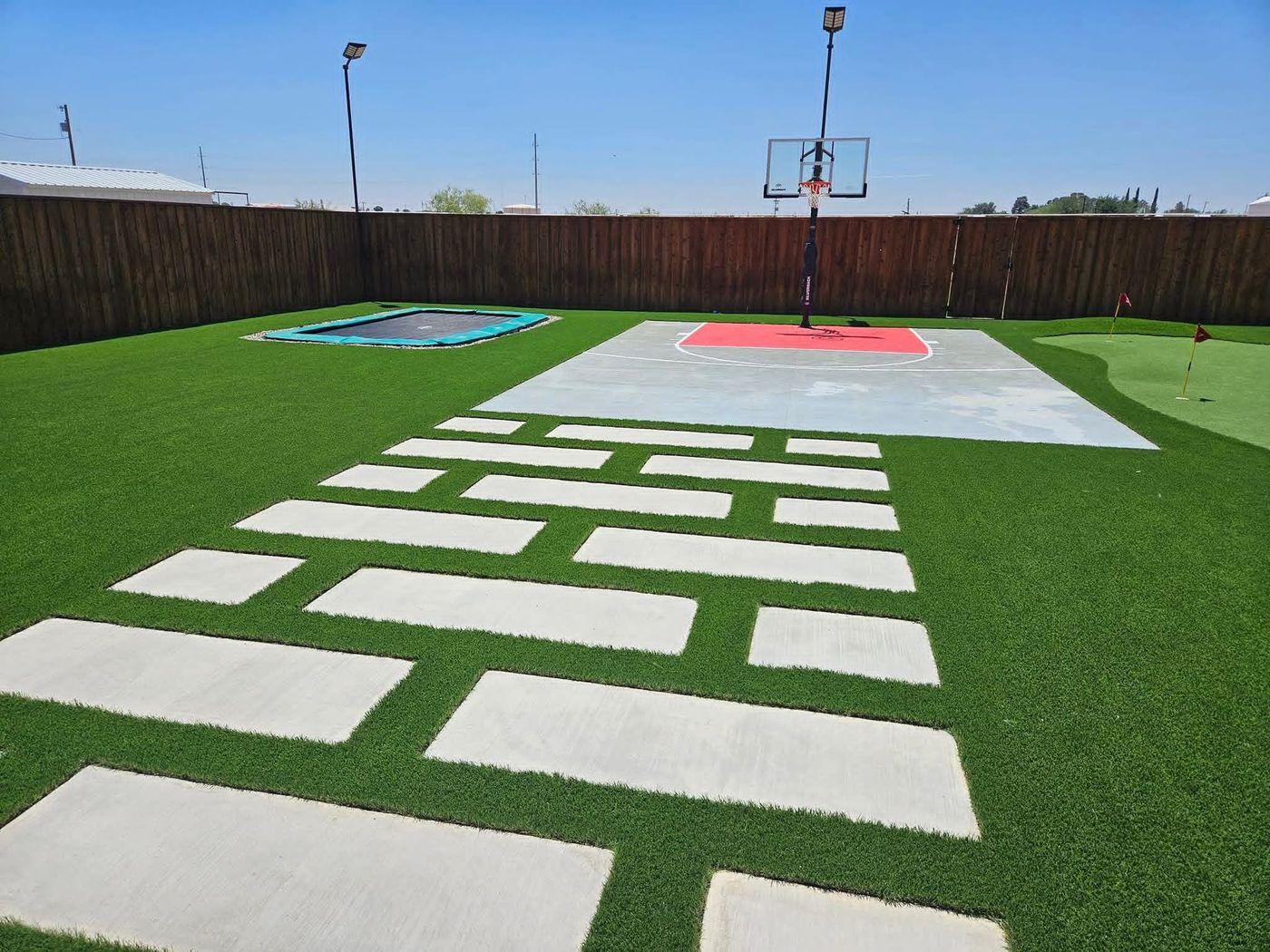 Backyard basketball half-court with in-ground trampoline and putting green in Legacy South, Midland TX