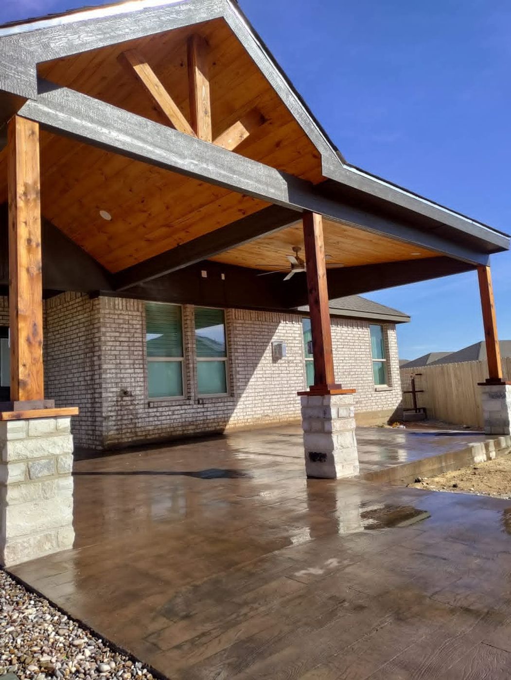 Gable-roof covered patio with vaulted cedar tongue-and-groove ceiling and timber trusses in Lone Star Trails, Midland TX