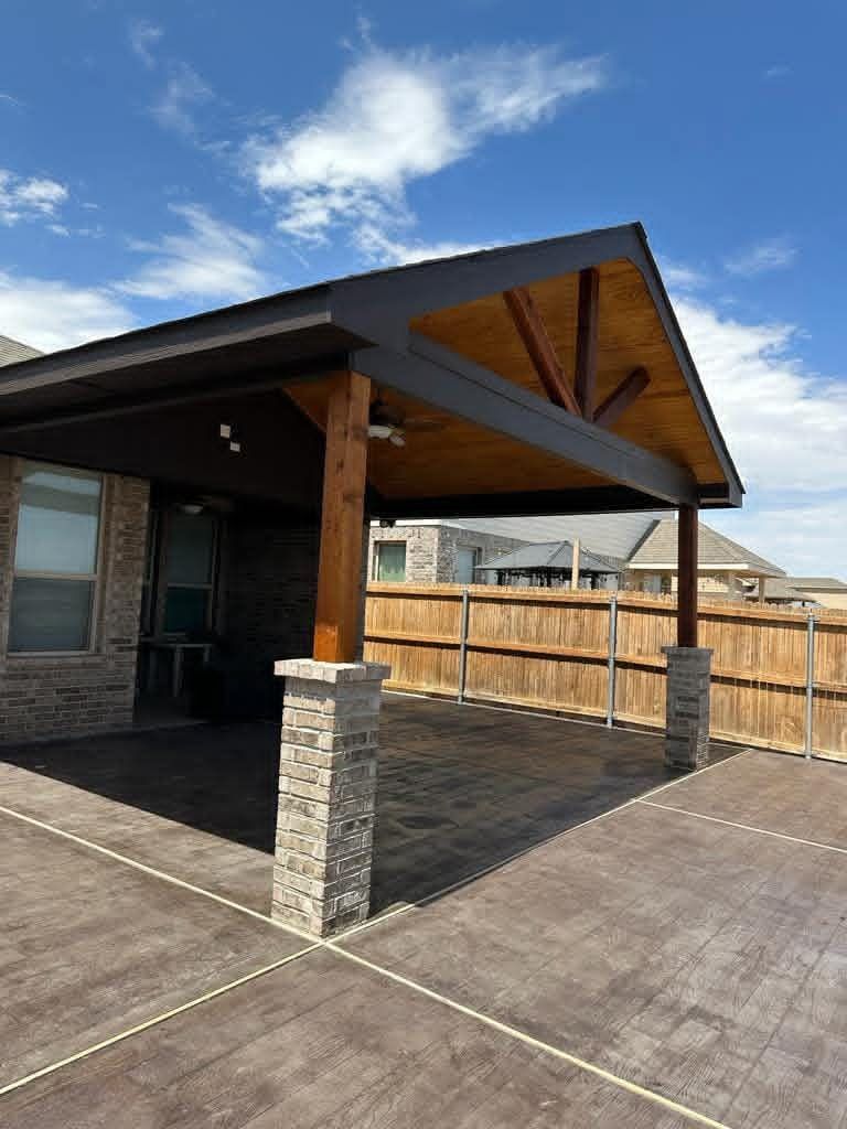 Covered patio with cedar gable ceiling and brick-veneer column base over stamped concrete in Lone Star Trails, Midland TX