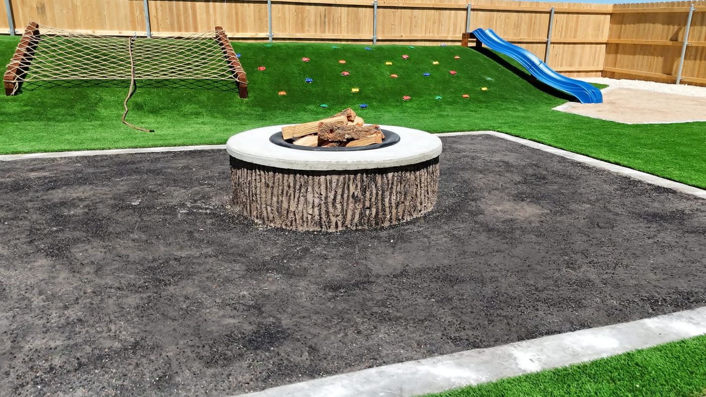 Custom concrete fire pit on a decomposed-granite court with turf play berm in Northwest Passage, Midland TX