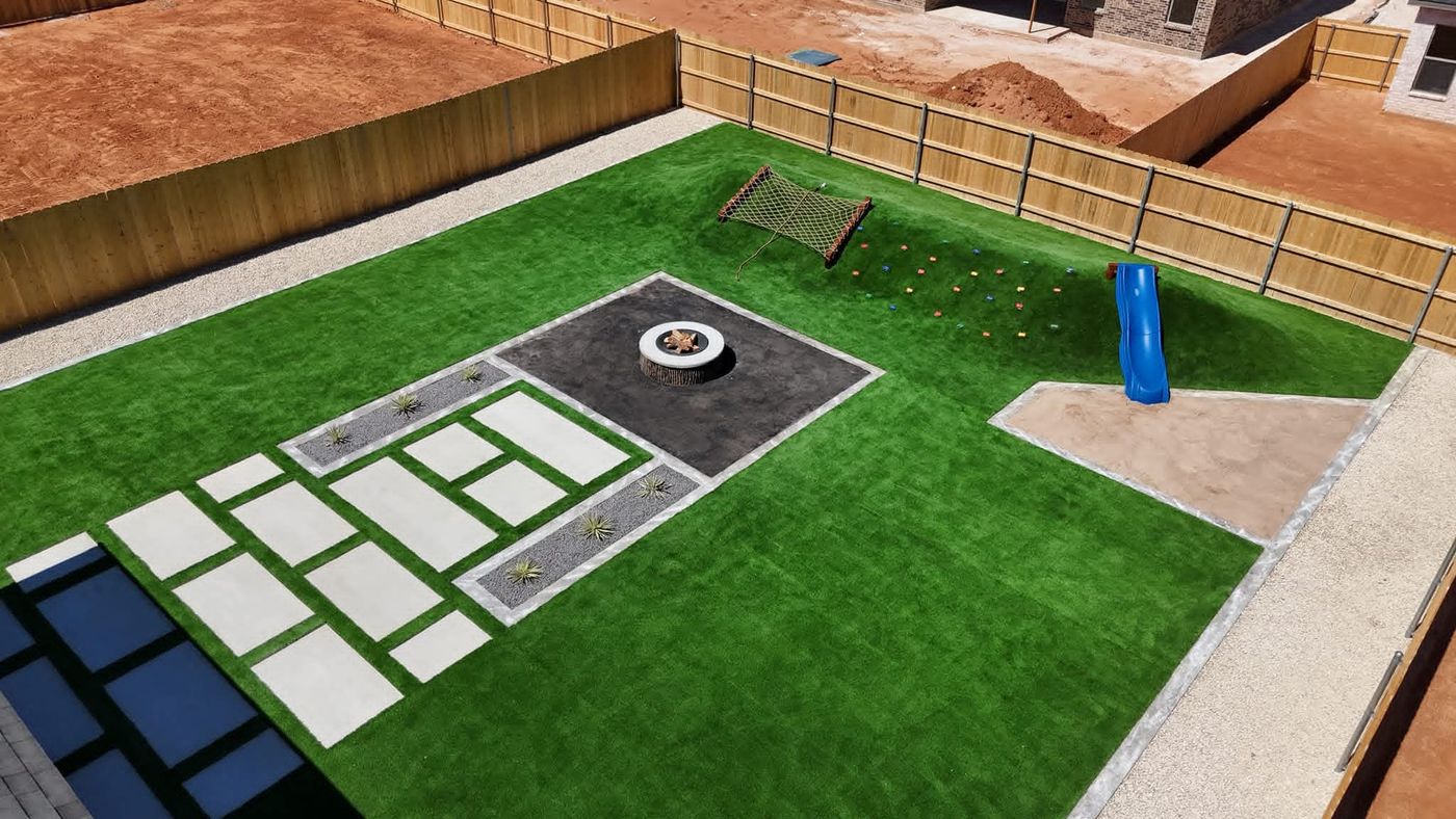 Aerial of turf yard with paver pathway, gravel and yucca borders and fire-pit pad in Northwest Passage, Midland TX