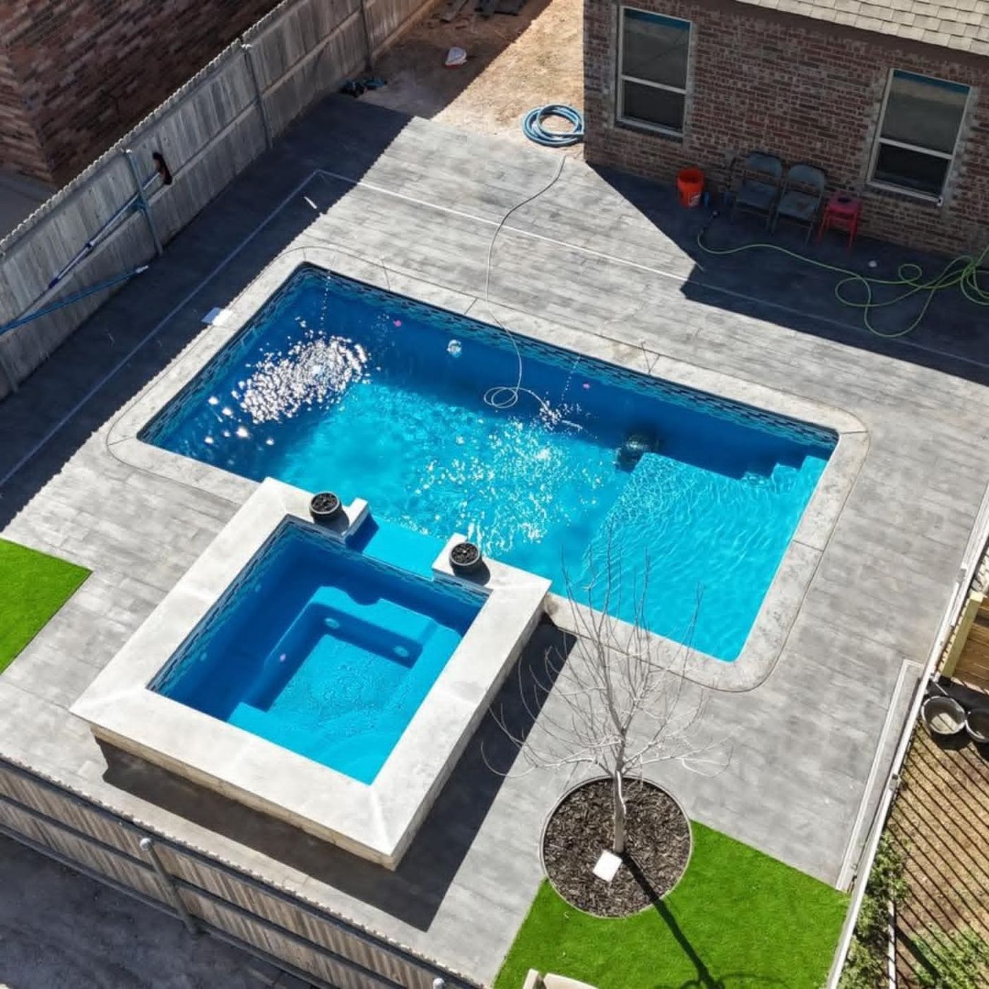 Fiberglass pool with raised spillover spa and decorative concrete deck in Northwest Passage, Midland TX