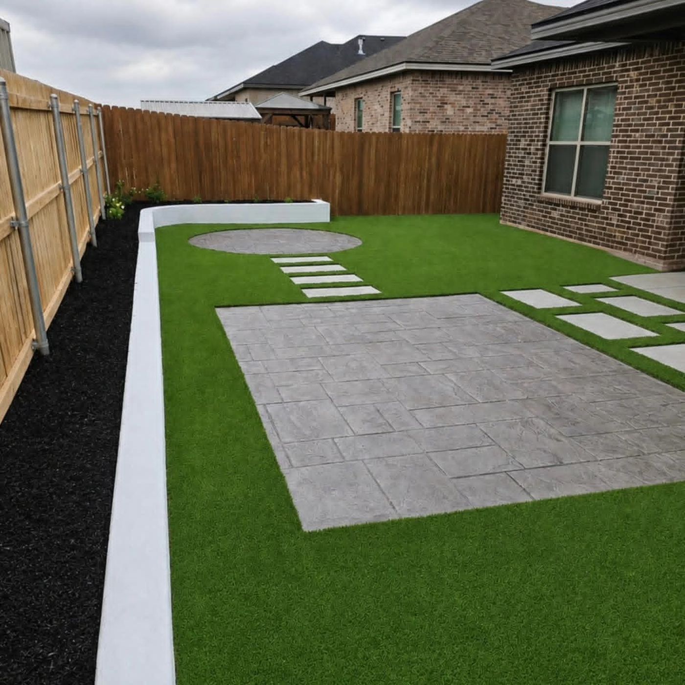 Artificial turf backyard with ashlar stamped-concrete patio, circular paver pad and stepping stones in Windmill Crossing, Odessa TX