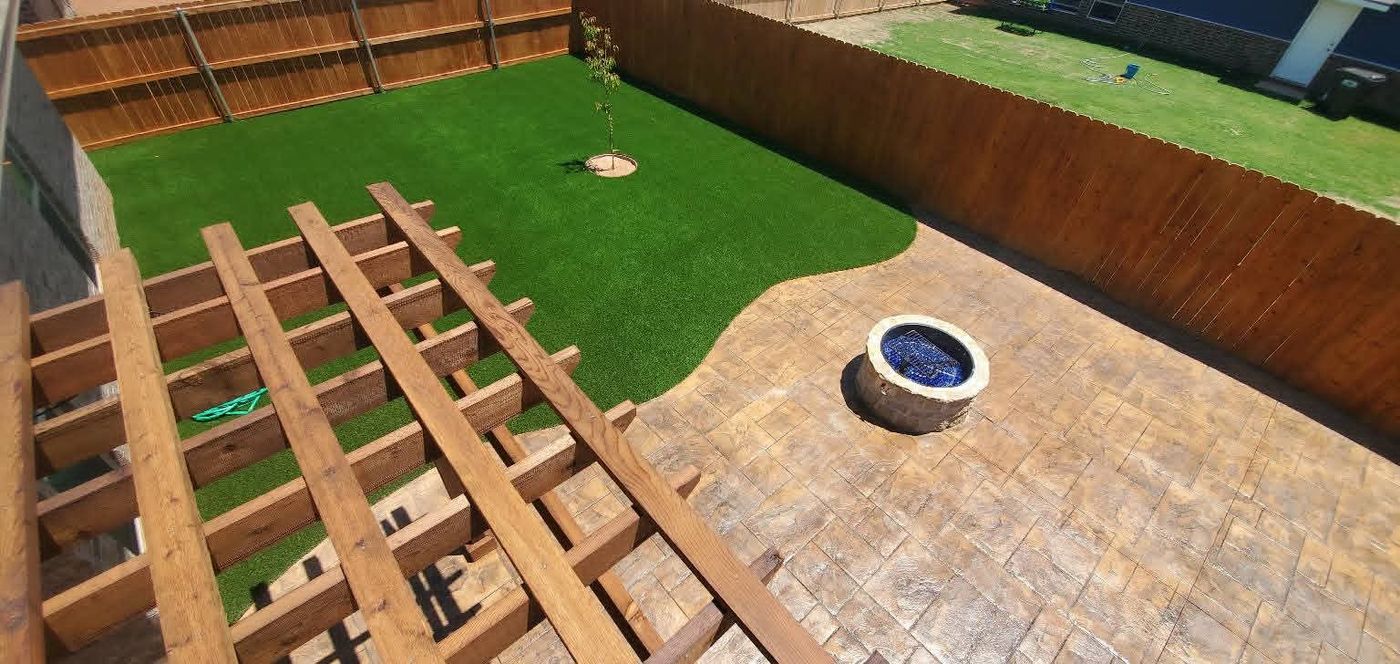 Cedar pergola over stamped-concrete patio with round stone fire pit and turf lawn in Windmill Crossing, Odessa TX